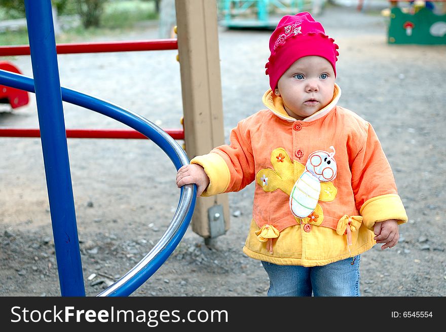 Pretty little girl stay near slide on playground. Pretty little girl stay near slide on playground.