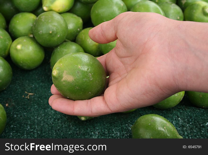 Hand holding a lime at an outdoor market. Hand holding a lime at an outdoor market.