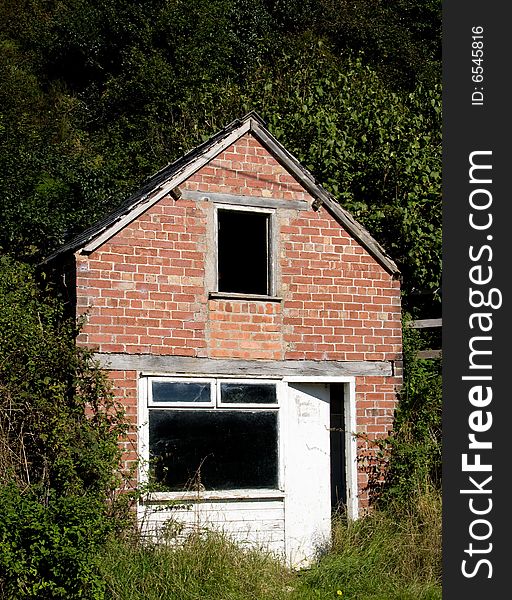 Small ruined house or cottage surrounded by trees and leaves. Small ruined house or cottage surrounded by trees and leaves