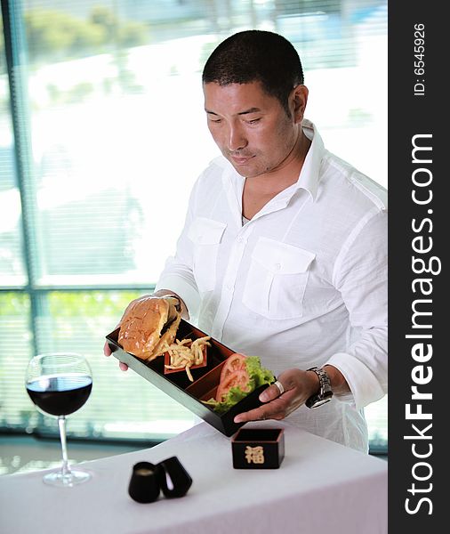 Asian Male waiter at table with hamburger