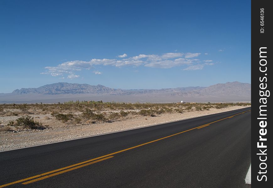 The yellow, no crossing line on raod through desert, hills in background. The yellow, no crossing line on raod through desert, hills in background.