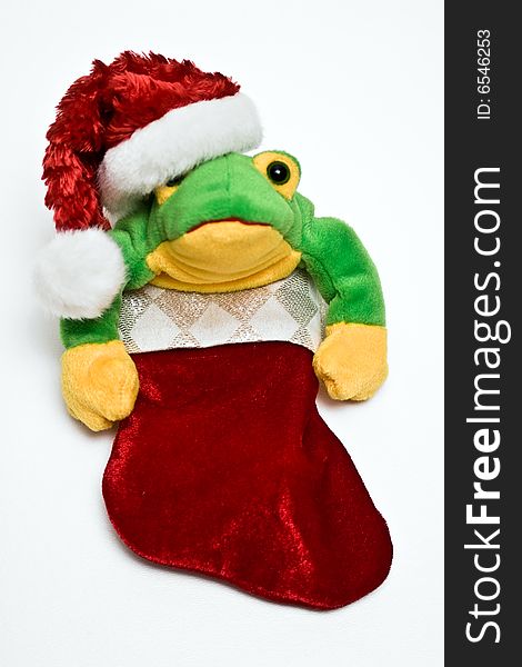 Stuffed frog toy wearing a santa hat while in a little red stocking. Stuffed frog toy wearing a santa hat while in a little red stocking.