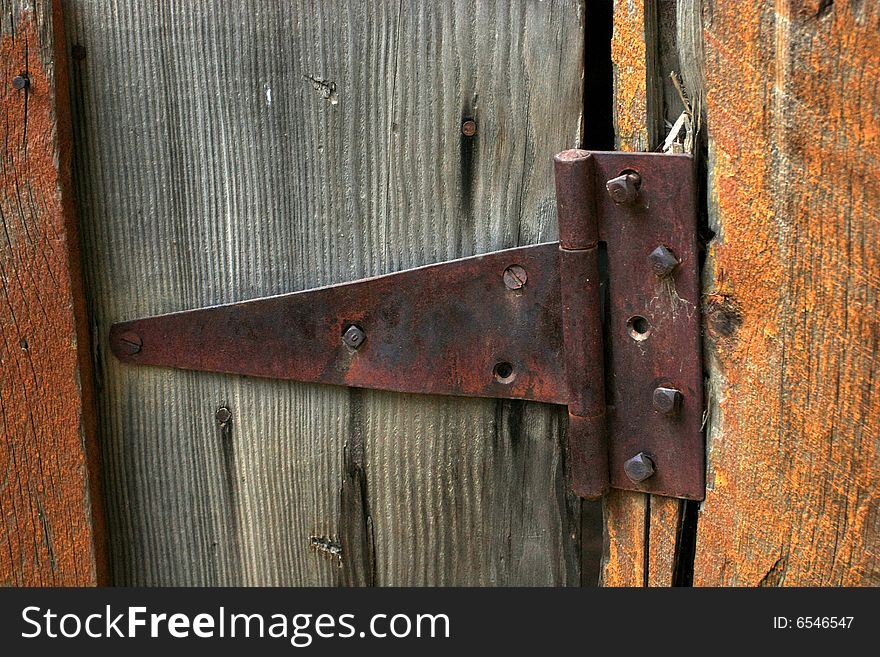 Texture shot of rusty worn antique hinge on old wood building