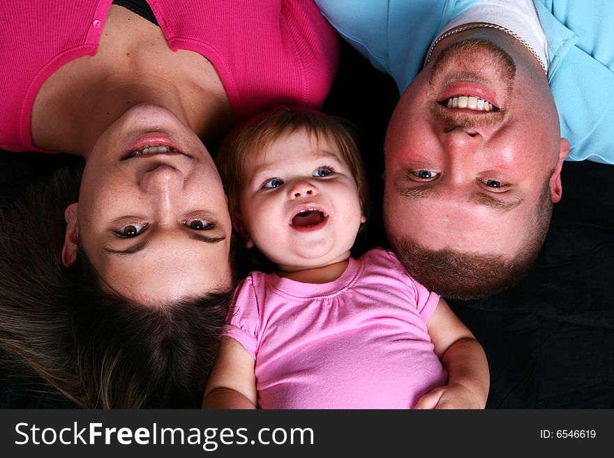 A mother, father and daughter looking up at the camera. A mother, father and daughter looking up at the camera