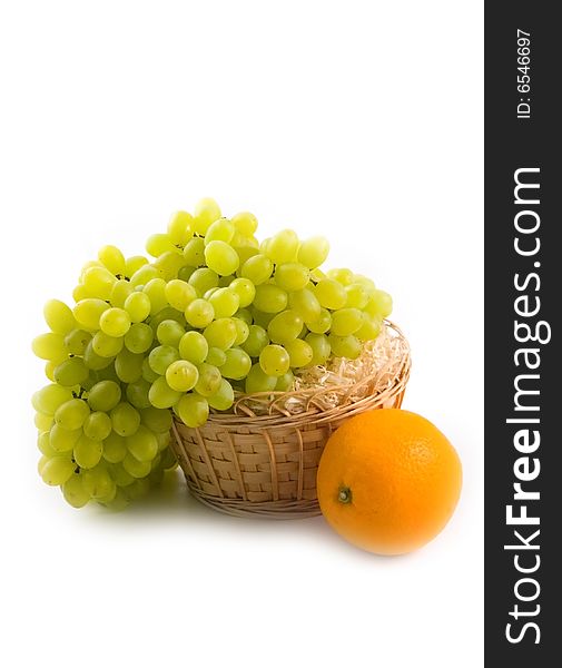 Yellow basket with green grapes and beautiful ripe orange on white background