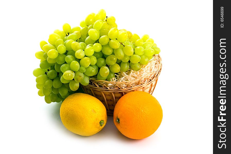 Yellow basket with green grapes and citruses orange lemon beside on white background