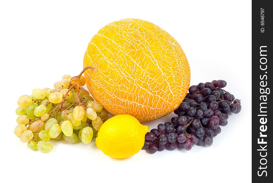 Ripe yellow melon and lemon with green and black grapes on white background