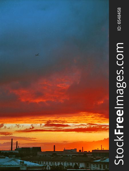 Industrial evening landscape with landing airplane