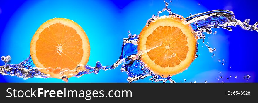Close up view of two sliced orange pieces getting splashed with water. Close up view of two sliced orange pieces getting splashed with water