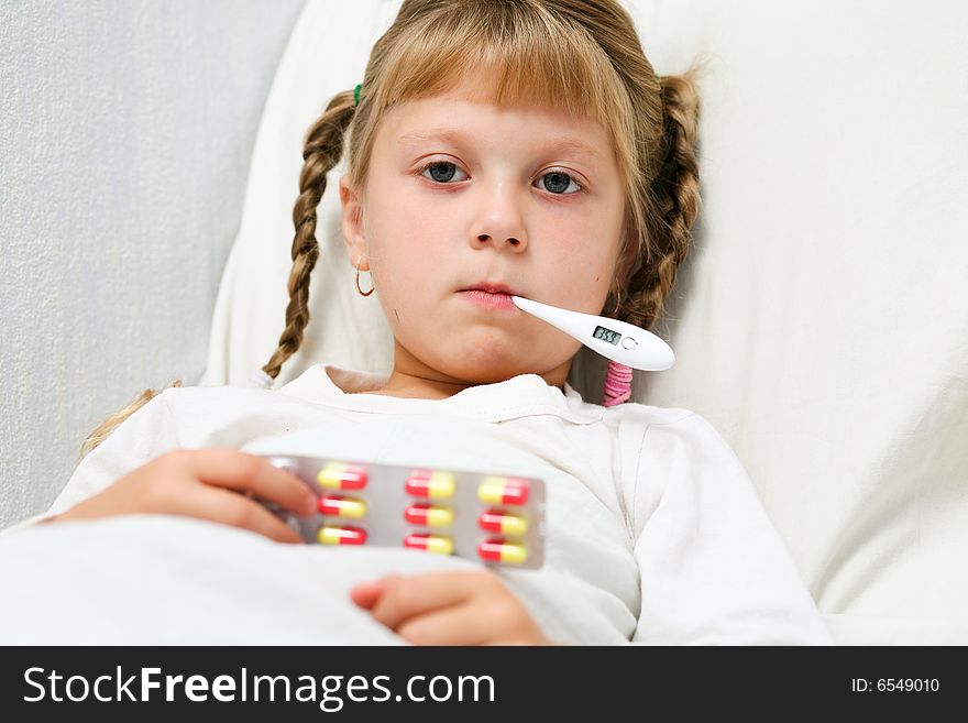 Young girl in bed with thermometer in mouth
