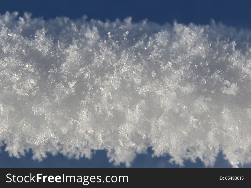 Snow and ice hanging on a thin wire outdoors in winter.  A rope of compact snow stretching horizontally across the picture. Snow and ice hanging on a thin wire outdoors in winter.  A rope of compact snow stretching horizontally across the picture.