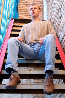 Young Stylish Man Sit On Stairs Near Brick Wall. Royalty Free Stock Images
