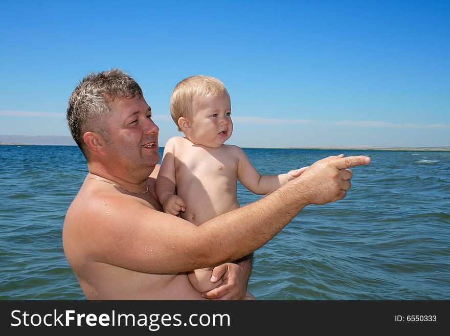 Father and his son look into the side on the beach. Father and his son look into the side on the beach