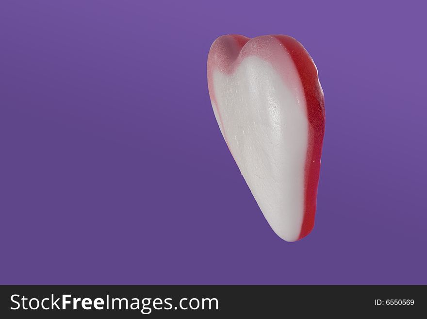 Pink, white and red candy heart isolated on purple background