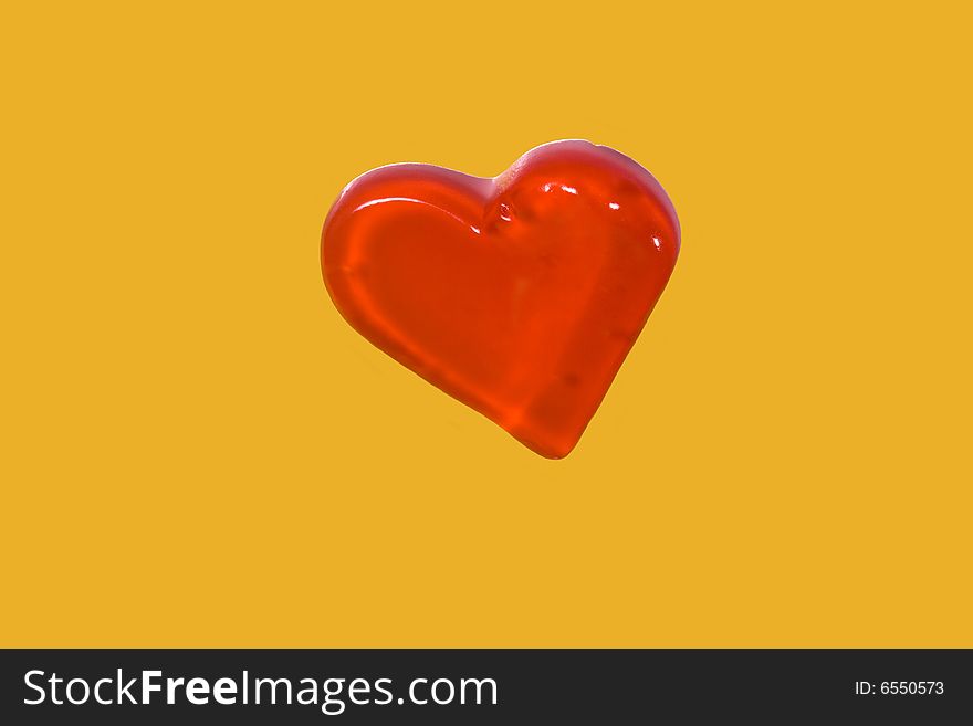 Red candy heart isolated on yellow background