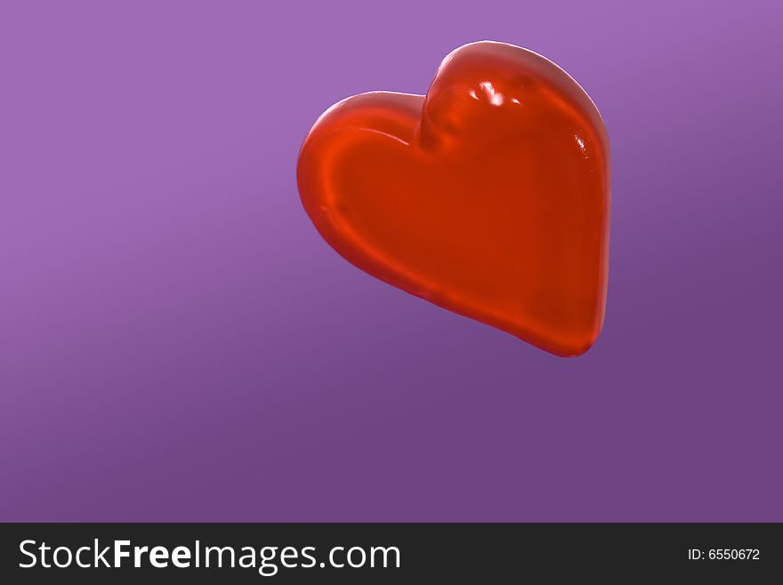 Red candy heart isolated on purple background
