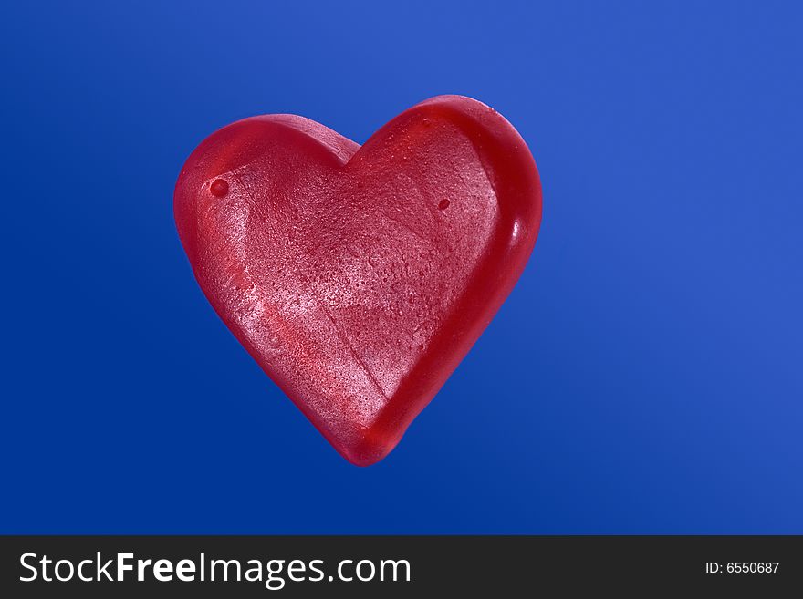 Red candy heart isolated on blue background