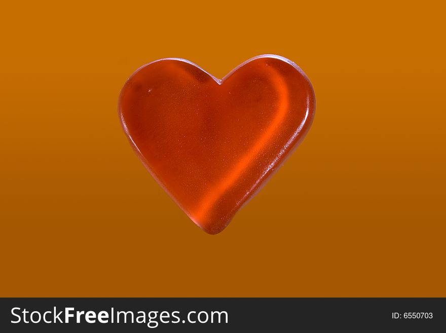 Red candy heart isolated on orange background