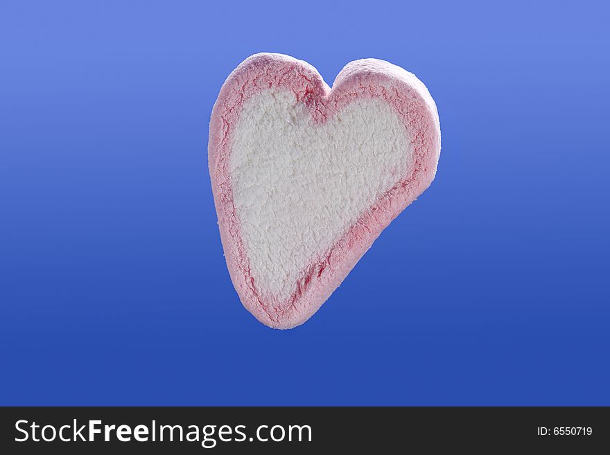 Pink and white marshmallow heart isolated on blue background. Pink and white marshmallow heart isolated on blue background