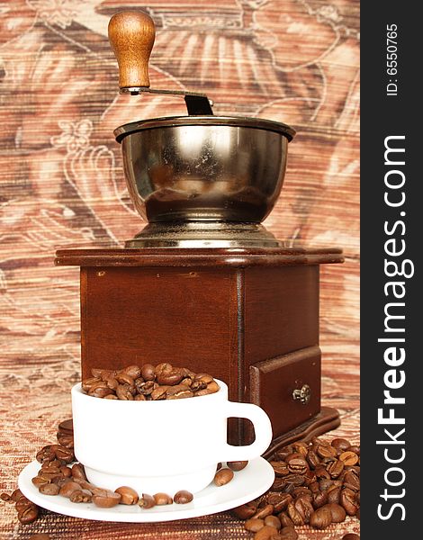 Old fashioned coffee grinder and  white cup with beans