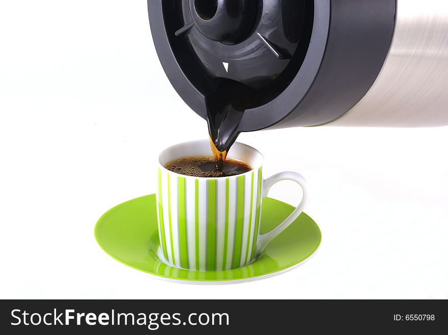Coffee being poured out of a pot into a cup with saucer. Coffee being poured out of a pot into a cup with saucer.