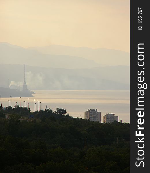 Urban scenery, city with residential area, petrochemical industry (smoke, pollution) and nature (sea and mountains) at dawn. Urban scenery, city with residential area, petrochemical industry (smoke, pollution) and nature (sea and mountains) at dawn