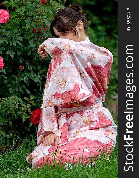 Girl in a pink yukata near rosebush. Girl in a pink yukata near rosebush