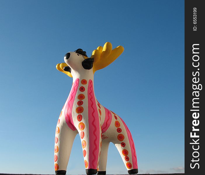 The golden antlers stag from fire-clay on the blue sky background. Hand made Dymka-toy. Russian national traditional toy from Vyatka town. The golden antlers stag from fire-clay on the blue sky background. Hand made Dymka-toy. Russian national traditional toy from Vyatka town.