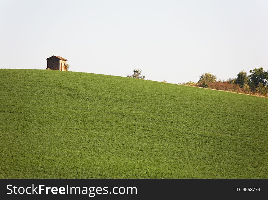 Rural construction at the top of a green hill, Piedmont, Italy