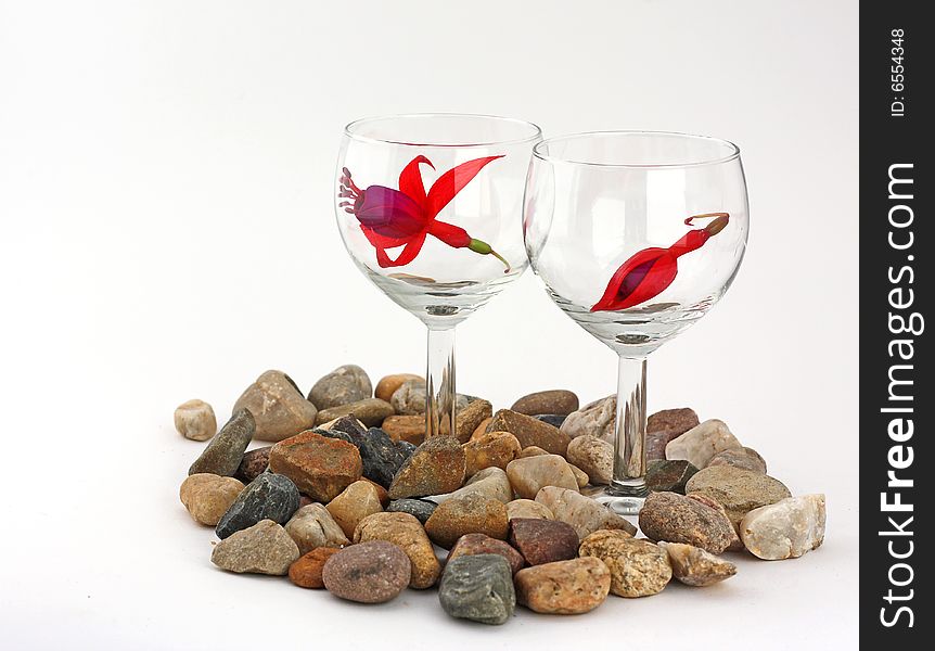 Red blossom inside of wineglasses and pebbles, white background