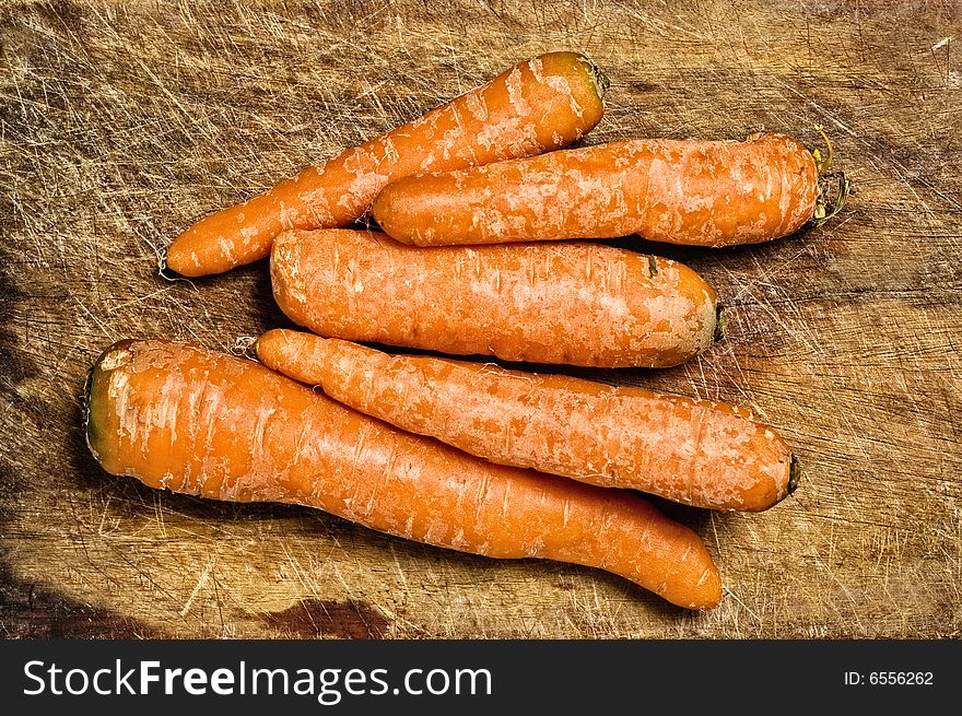 Bunch of carrots over an old wooden table.