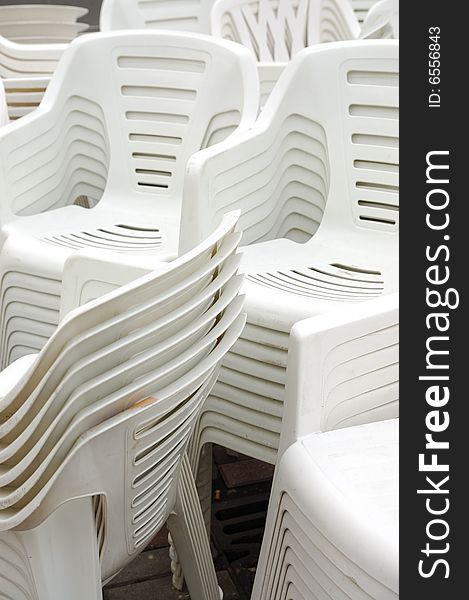 Stack of white plastic chairs on the street