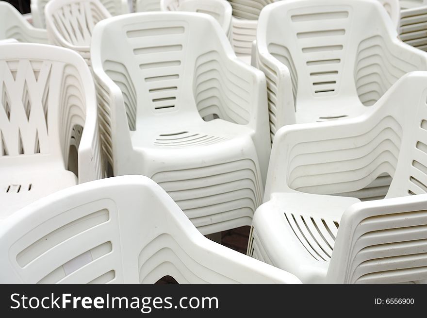 Stack of white plastic chairs on the street