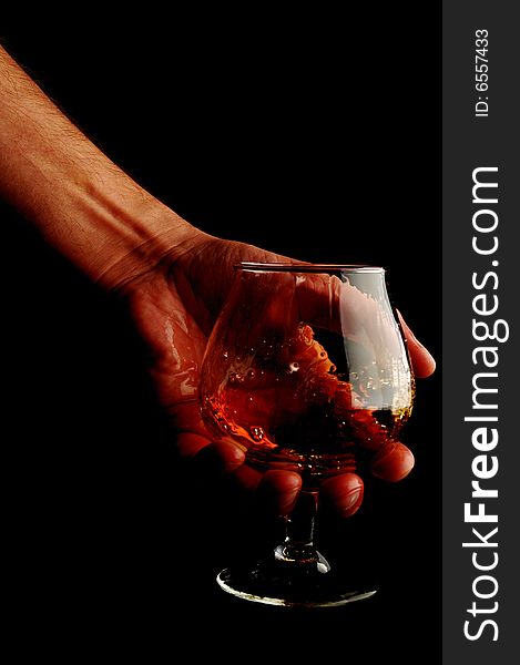 Man's hand holding a glass of brandy