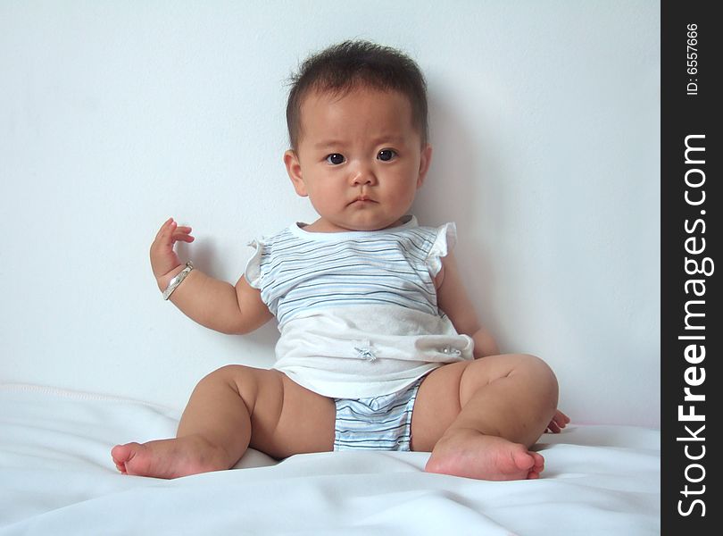 A cute baby is playing on a bed. A cute baby is playing on a bed