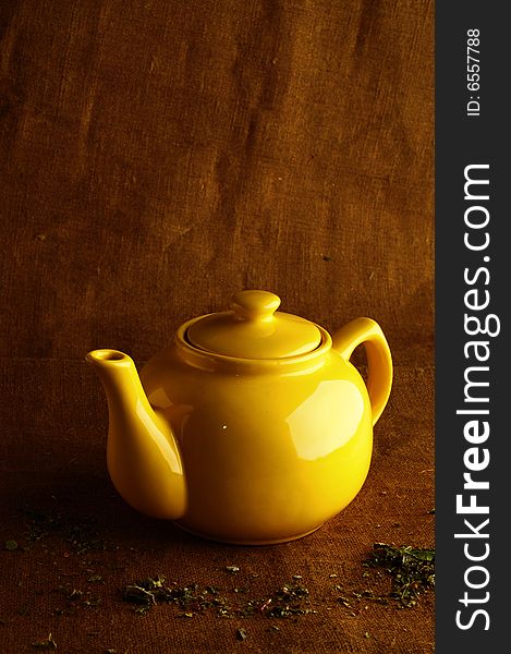 Yellow teapot on brown backdrop