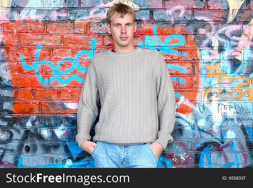 Young stylish man stand near graffiti brick wall.