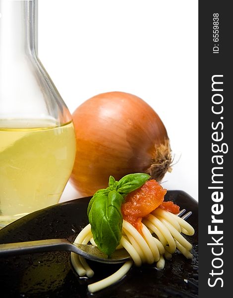 Spaghetti with fresh tomato and basil, with onion and olive oil in background