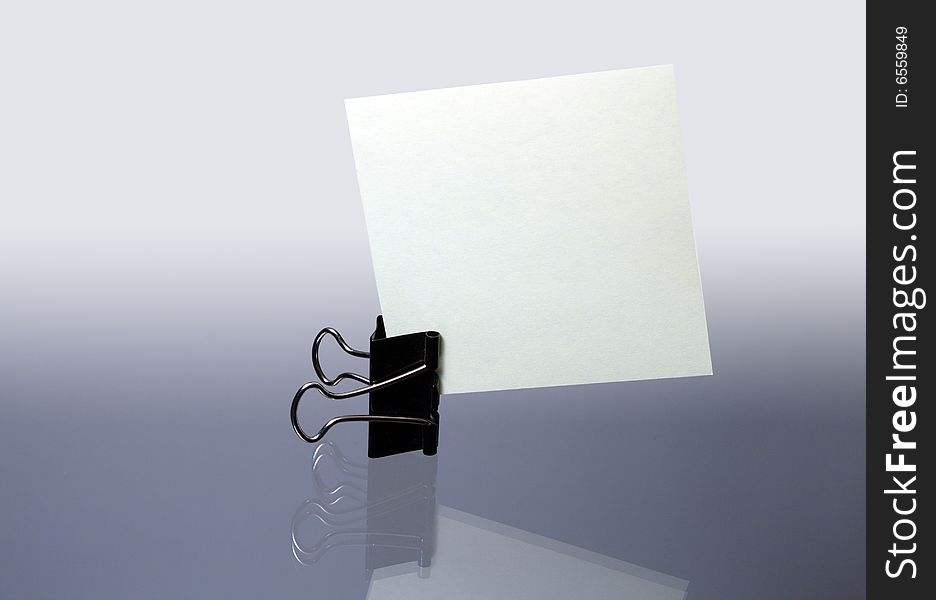 Office fastener with sheet paper standing on gray background. Office fastener with sheet paper standing on gray background