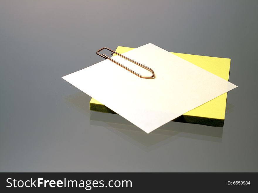 Little sheets of paper fastened with clip on gray background. Little sheets of paper fastened with clip on gray background