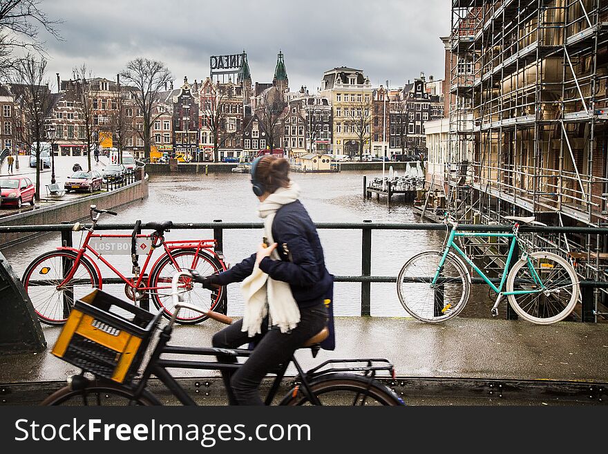 Amsterdam view with a girl on bicycle looking towards a canal.
