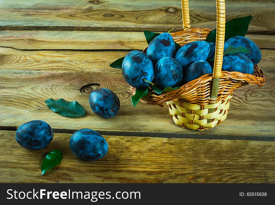 Fruit plum prunes in a basket on an old dark wooden background. Selective focus. Fruit plum prunes in a basket on an old dark wooden background. Selective focus