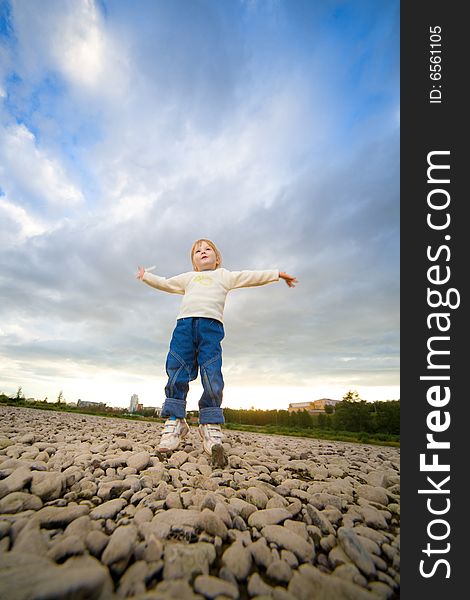 Little girl jump under blue sky with clouds