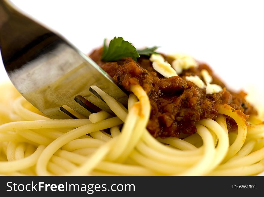 Close up of spaghetti  bolognaise with meat topping with a fork digging in .