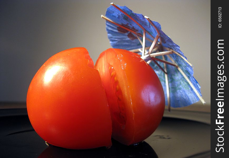 Ripe tomato cut on half with party umbrella. Ripe tomato cut on half with party umbrella.