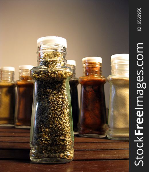Oregano in glass jar and other spices standing behind. Oregano in glass jar and other spices standing behind.