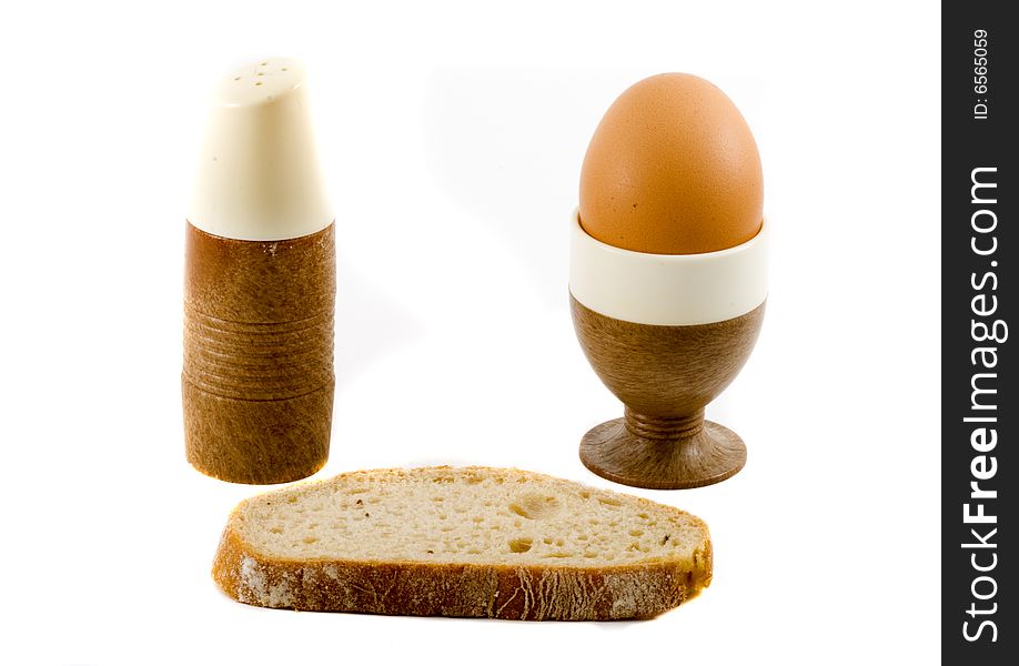 A soft boiled egg, a slice of bread and a saltpot