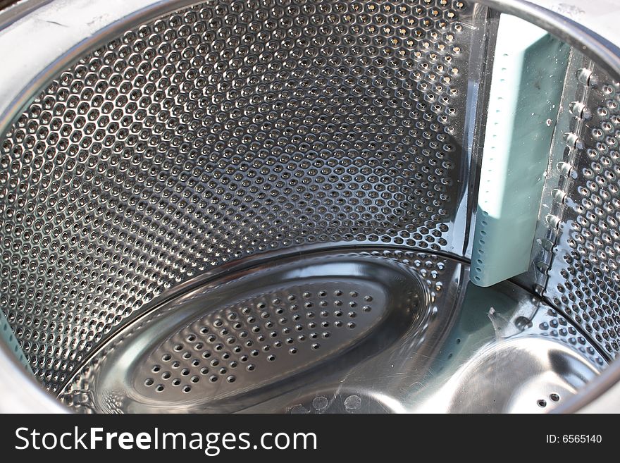 The inside of a shiny washing machine stainless steel drum. The inside of a shiny washing machine stainless steel drum
