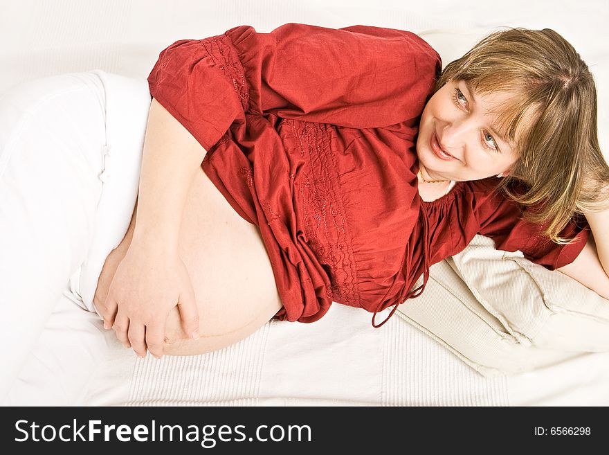A pregnant lady with a red shirt touching her stomach. A pregnant lady with a red shirt touching her stomach