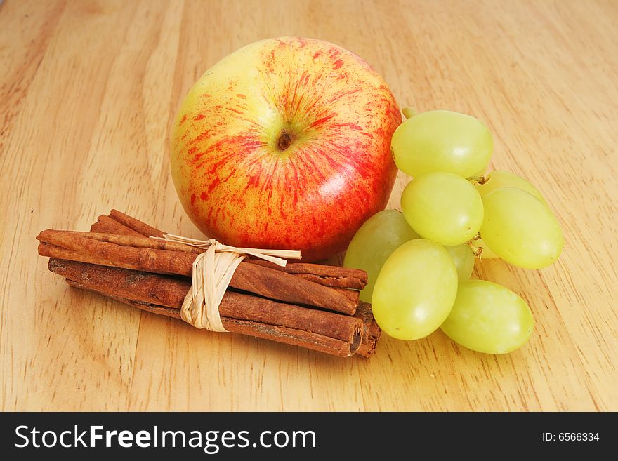 Apple grapes and cinnamon on a wooden board. Apple grapes and cinnamon on a wooden board